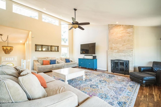 living room featuring dark wood-type flooring, a fireplace, a high ceiling, and ceiling fan