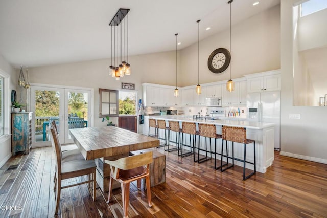 dining space featuring dark wood-type flooring, french doors, and a towering ceiling