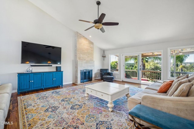 living room featuring ceiling fan, dark hardwood / wood-style floors, a stone fireplace, and high vaulted ceiling