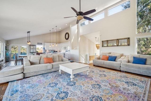 living room featuring ceiling fan, hardwood / wood-style floors, and a towering ceiling