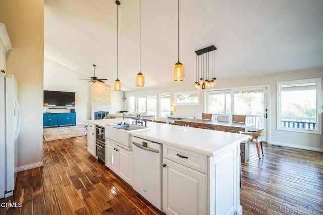 kitchen with white appliances, white cabinetry, dark hardwood / wood-style floors, ceiling fan, and a center island with sink