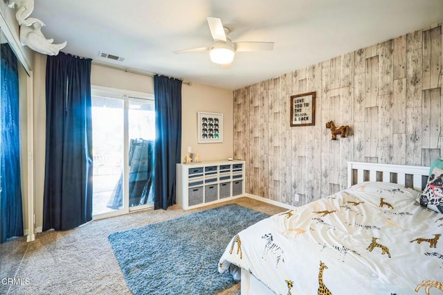 bedroom featuring ceiling fan, access to outside, wooden walls, and carpet flooring