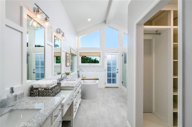 bathroom featuring vanity, independent shower and bath, and vaulted ceiling with beams