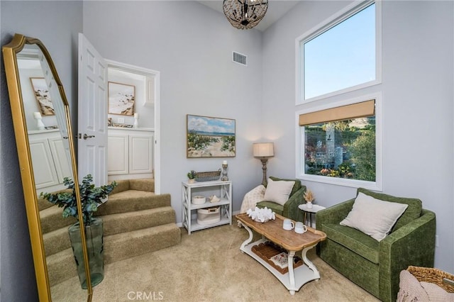 living room featuring carpet, a towering ceiling, and a chandelier