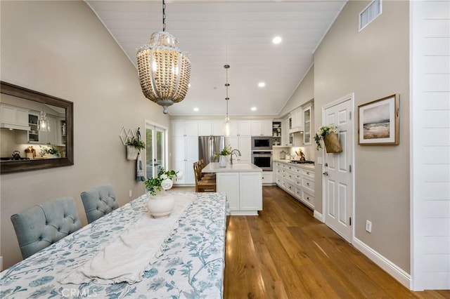 dining room with lofted ceiling, light wood-type flooring, sink, and a chandelier