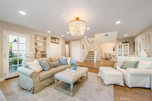 living room featuring an inviting chandelier, light hardwood / wood-style floors, and built in features