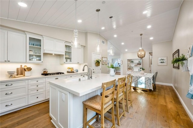 kitchen featuring decorative backsplash, vaulted ceiling, gas stovetop, and a center island with sink