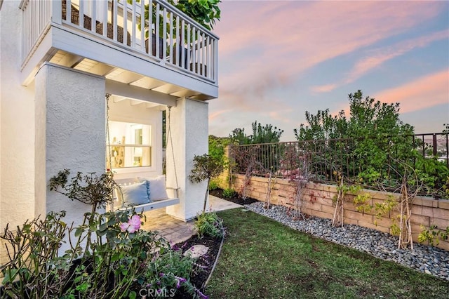 yard at dusk featuring a balcony