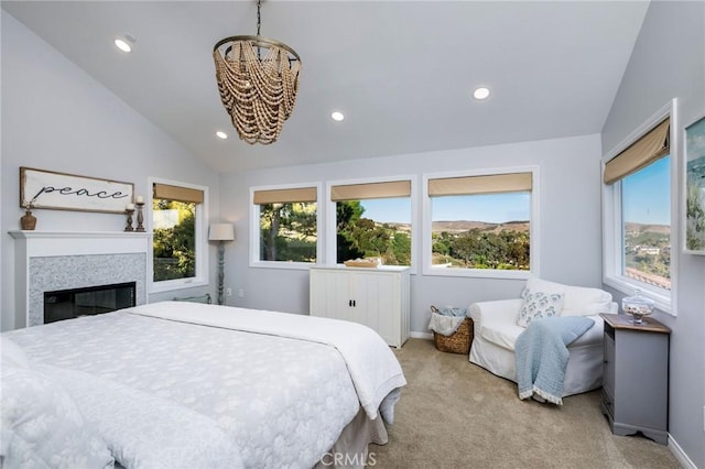 bedroom with light colored carpet, multiple windows, a tiled fireplace, and vaulted ceiling