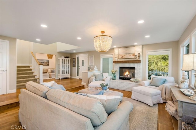 living room with a brick fireplace, light hardwood / wood-style flooring, and a chandelier