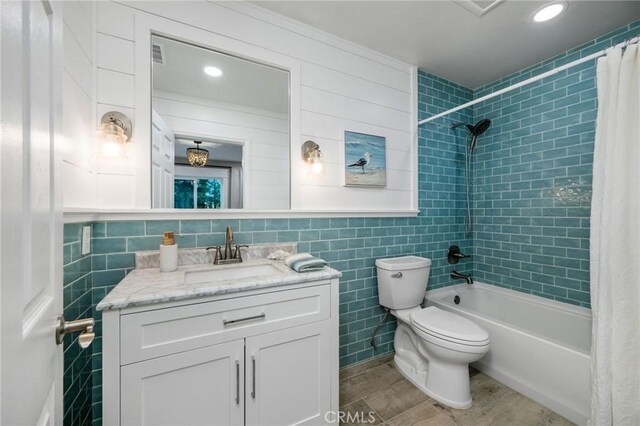 full bathroom with toilet, tile walls, vanity, and shower / tub combo with curtain