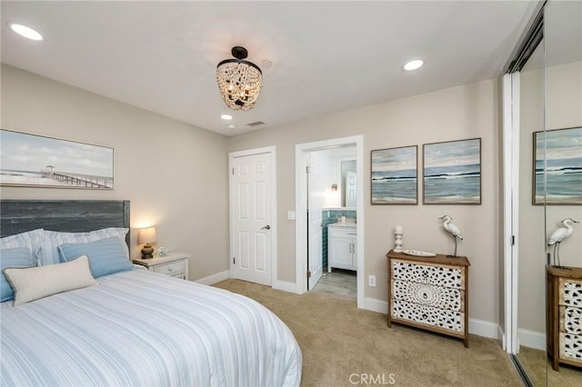 bedroom with light colored carpet, connected bathroom, and an inviting chandelier