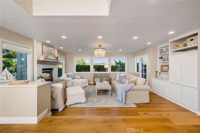 living room with a fireplace, a chandelier, and light wood-type flooring