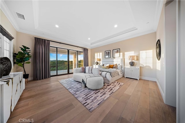 bedroom with a raised ceiling, access to outside, light wood-type flooring, and ornamental molding