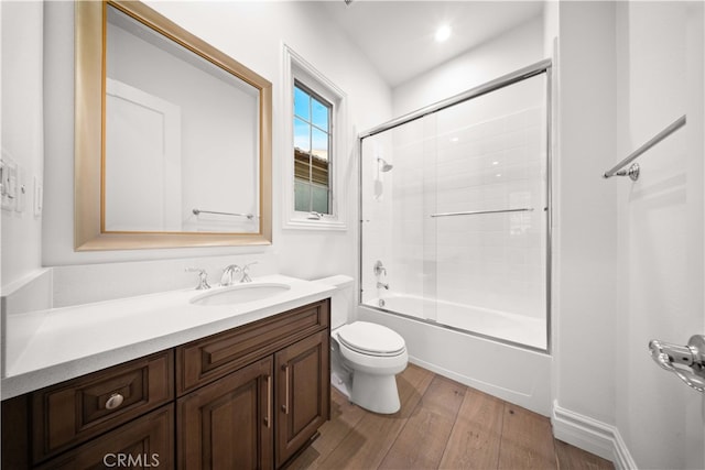 full bathroom with wood-type flooring, combined bath / shower with glass door, vanity, and toilet