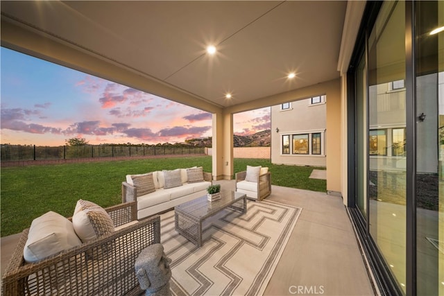 patio terrace at dusk with an outdoor living space and a lawn