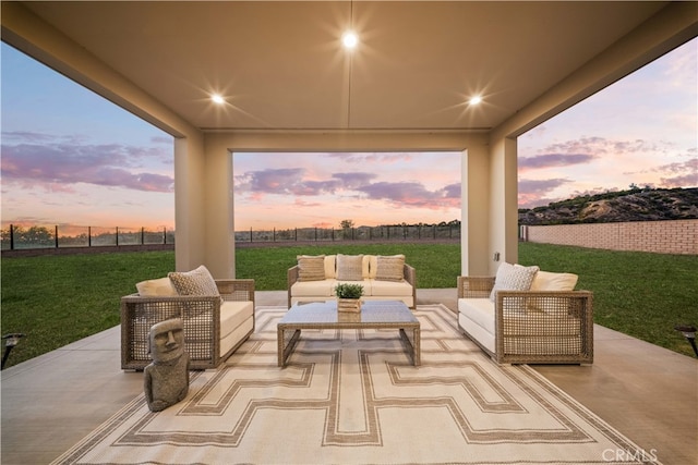 patio terrace at dusk featuring an outdoor living space and a yard