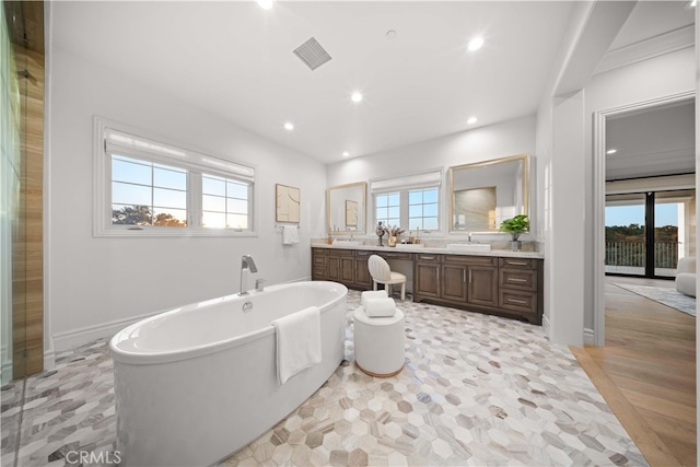 bathroom featuring wood-type flooring, a bath, a healthy amount of sunlight, and vanity