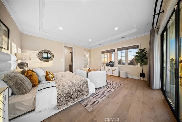 bedroom with light wood-type flooring, crown molding, and a raised ceiling