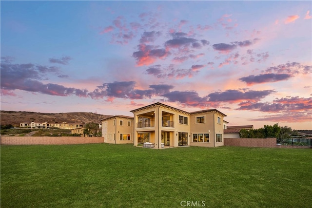 back house at dusk featuring a yard