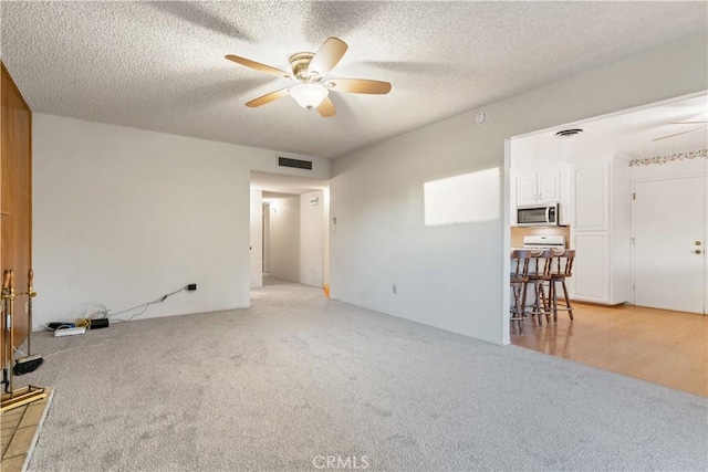 carpeted spare room featuring a textured ceiling and ceiling fan