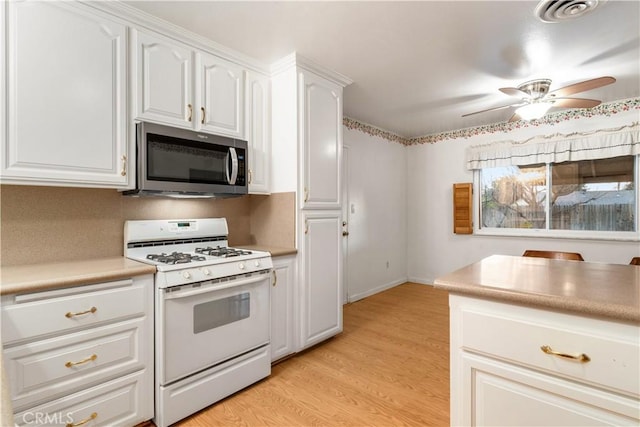 kitchen featuring ceiling fan, light wood-type flooring, white gas range, and white cabinetry