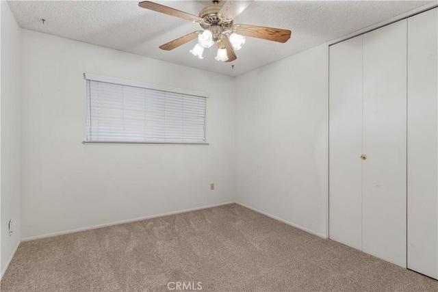 unfurnished bedroom with ceiling fan, light colored carpet, and a textured ceiling