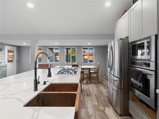 20276 Waco Rd, Apple Valley, CA 92308 - kitchen with appliances with stainless steel finishes, white cabinetry, sink, light stone counters, and light hardwood / wood-style flooring
