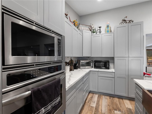 20276 Waco Rd, Apple Valley, CA 92308 - kitchen featuring light stone countertops, light wood-type flooring, appliances with stainless steel finishes, and gray cabinetry