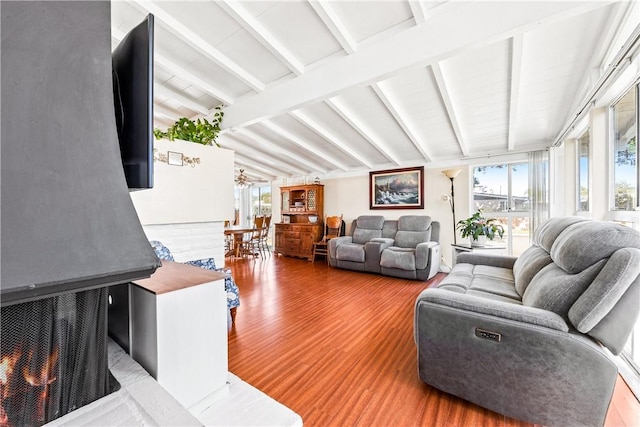 living room featuring hardwood / wood-style floors, a fireplace, and lofted ceiling with beams