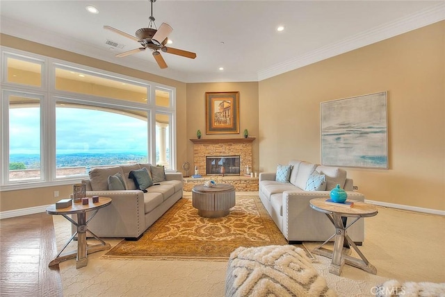 living room with ceiling fan, ornamental molding, and a stone fireplace