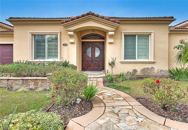 entrance to property featuring a garage and a lawn