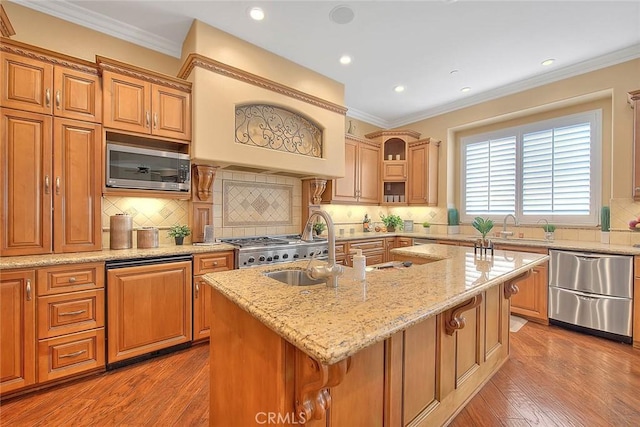 kitchen with light stone countertops, appliances with stainless steel finishes, a kitchen island with sink, and backsplash