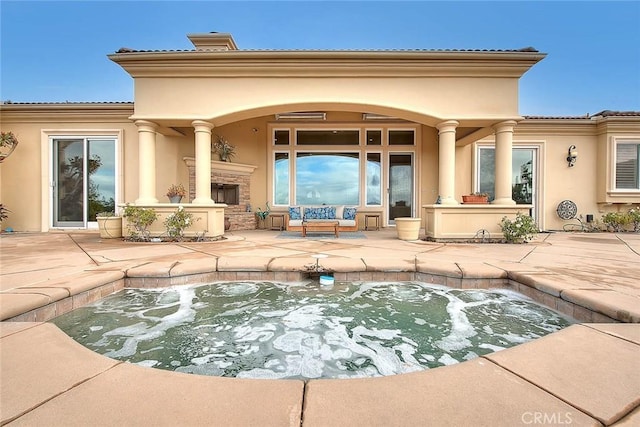 back of property with a fireplace and a patio