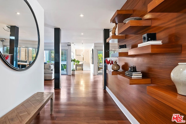 hall with wood-type flooring, a healthy amount of sunlight, and wooden walls