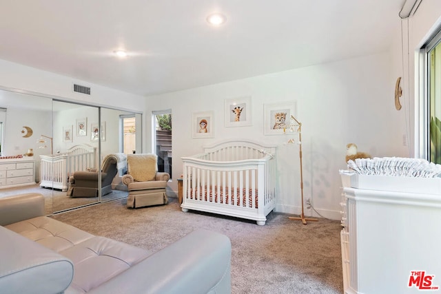 bedroom with a crib, carpet, and a closet