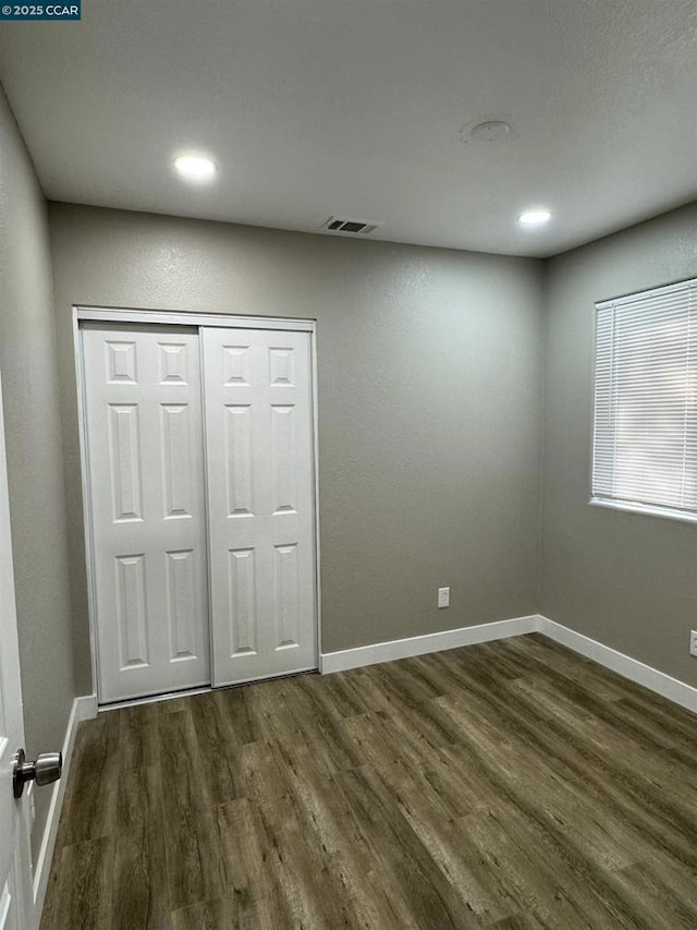 unfurnished bedroom with dark wood-type flooring and a closet