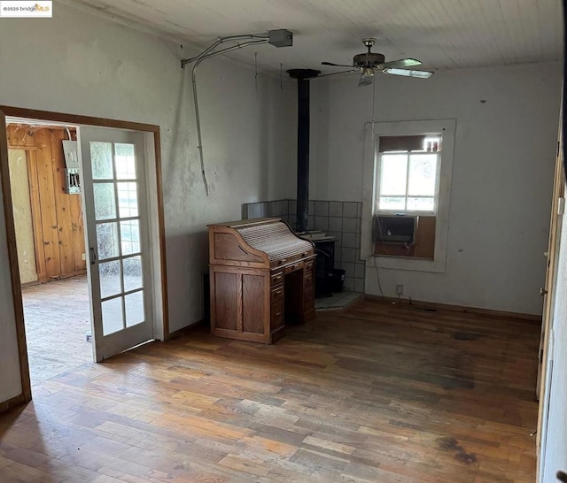 kitchen with ceiling fan, cooling unit, a wood stove, and wood-type flooring