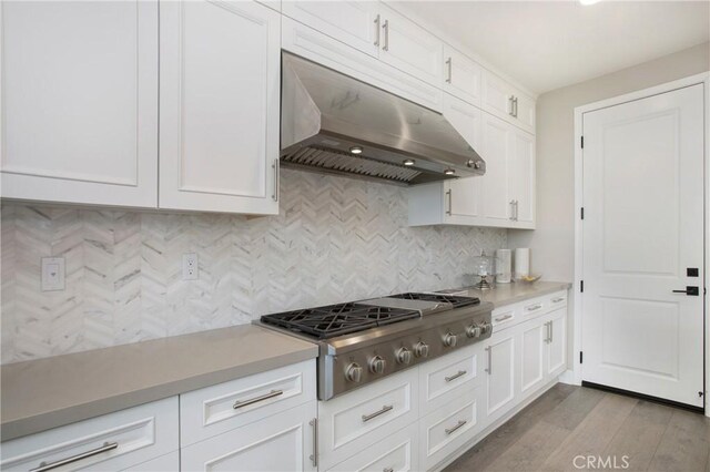 kitchen featuring light hardwood / wood-style floors, white cabinetry, decorative backsplash, and stainless steel gas stovetop