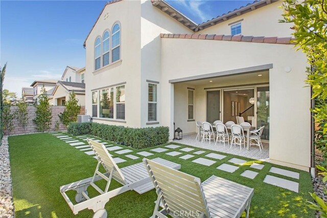 rear view of property with a lawn and a patio