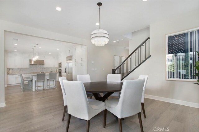 dining room with light hardwood / wood-style floors and a notable chandelier