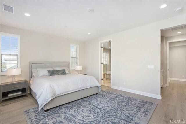 bedroom featuring connected bathroom and light wood-type flooring