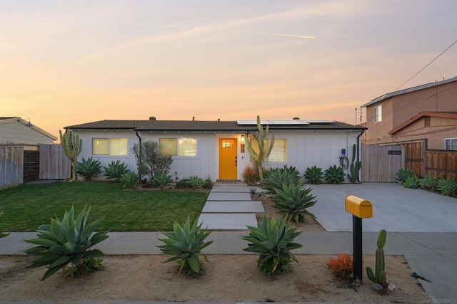 view of front of property with a yard and solar panels