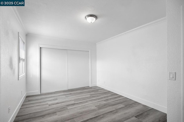 unfurnished bedroom with ornamental molding, light hardwood / wood-style floors, and a closet