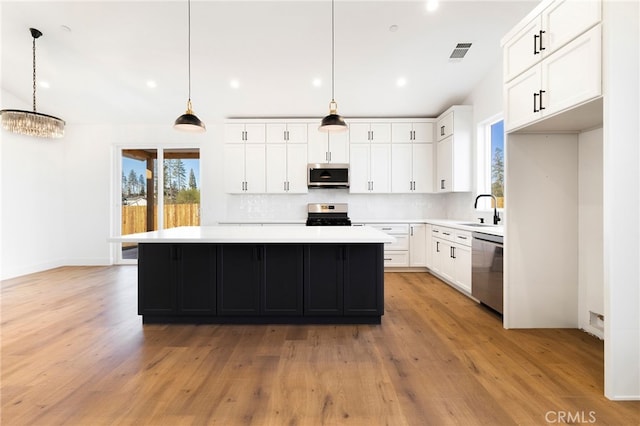 kitchen featuring white cabinets, appliances with stainless steel finishes, pendant lighting, and a center island