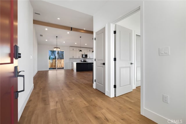 corridor with beam ceiling and light hardwood / wood-style floors