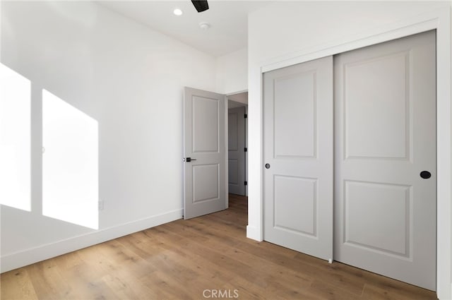 unfurnished bedroom with a closet, hardwood / wood-style floors, and ceiling fan