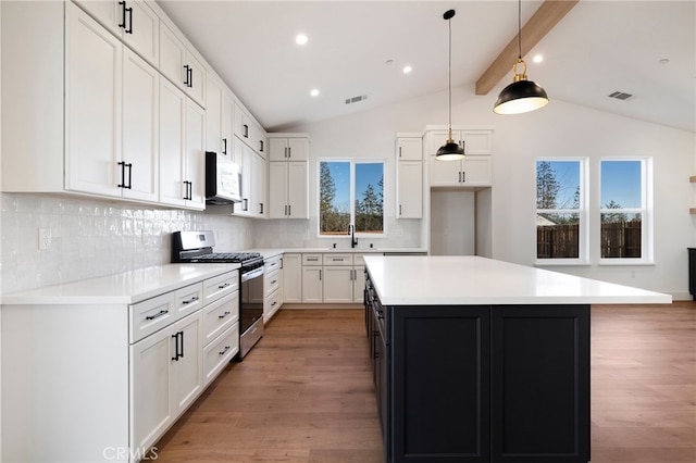 kitchen featuring stainless steel gas stove, backsplash, and white cabinets