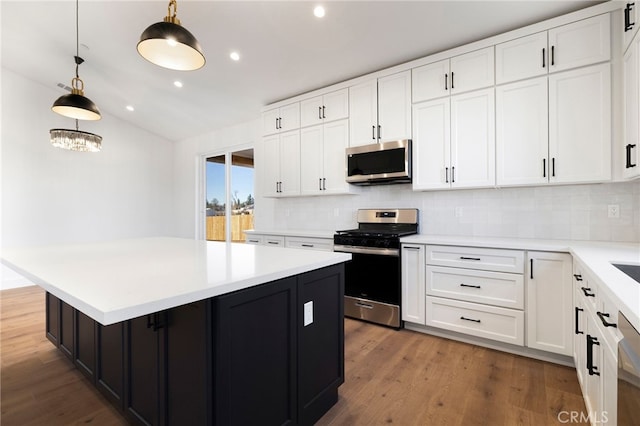 kitchen featuring white cabinets, a kitchen island, decorative light fixtures, stainless steel appliances, and backsplash