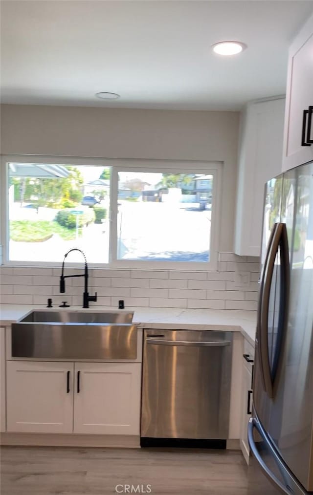 kitchen with sink, backsplash, white cabinets, a healthy amount of sunlight, and stainless steel appliances